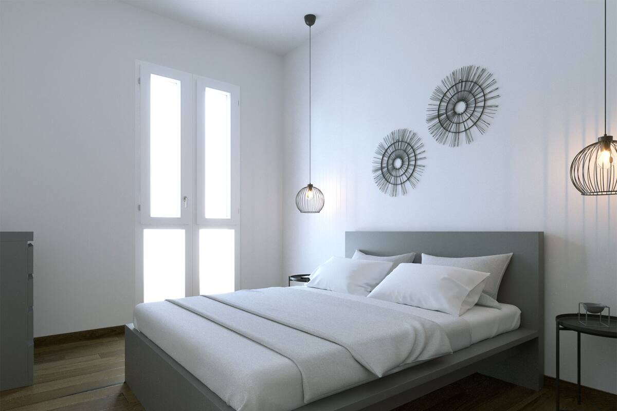 Une chambre à coucher moderne avec un grand lit, une table de chevet, un luminaire fixé au mur et une porte avec une fenêtre.