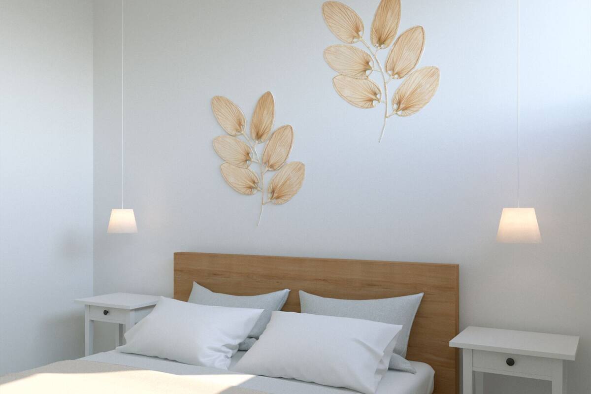 Une chambre à coucher moderne avec une tête de lit en bois, un grand lit avec une literie blanche, deux tables de chevet et des œuvres d’art murales.