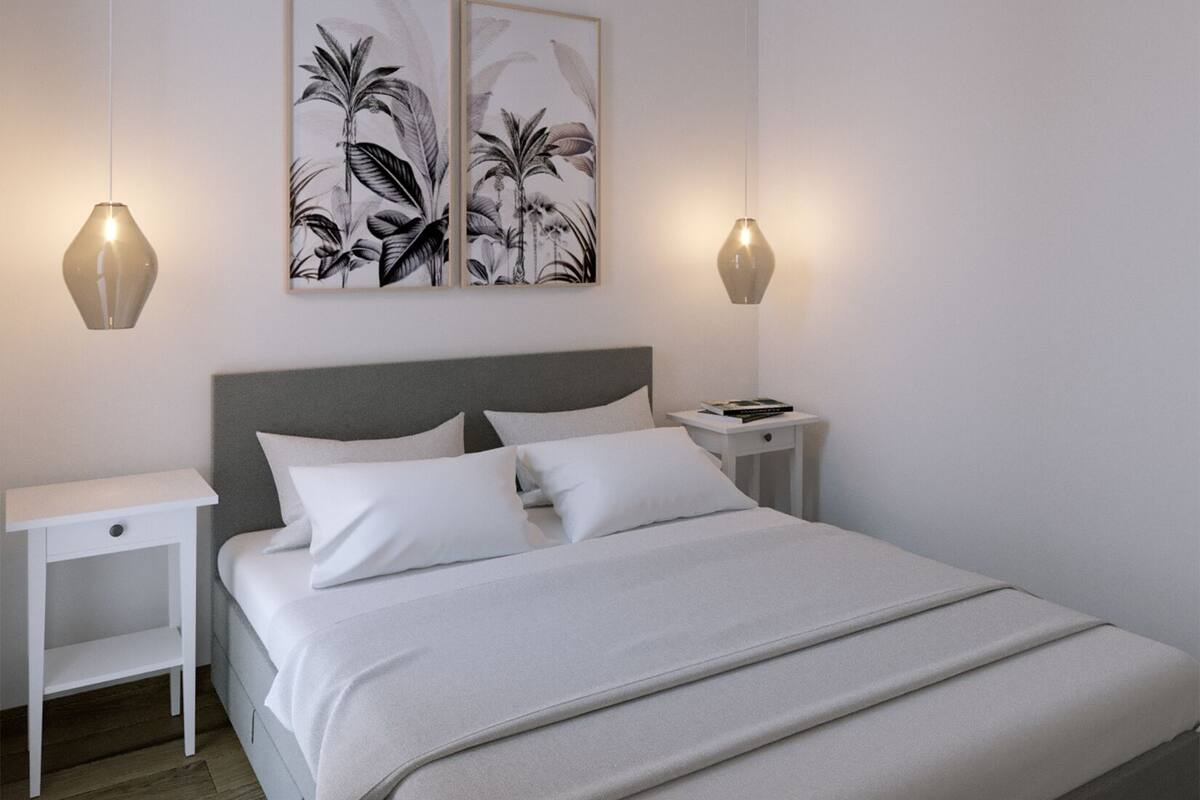 Une chambre à coucher bien rangée, avec un grand lit, deux tables de chevet et des lampes fixées au mur.