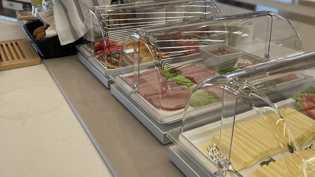 A buffet setup with various food items in clear containers, a striped cloth, and a vase with white flowers.