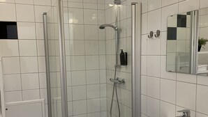 A modern bathroom with a shower, sink, and tiled floor.