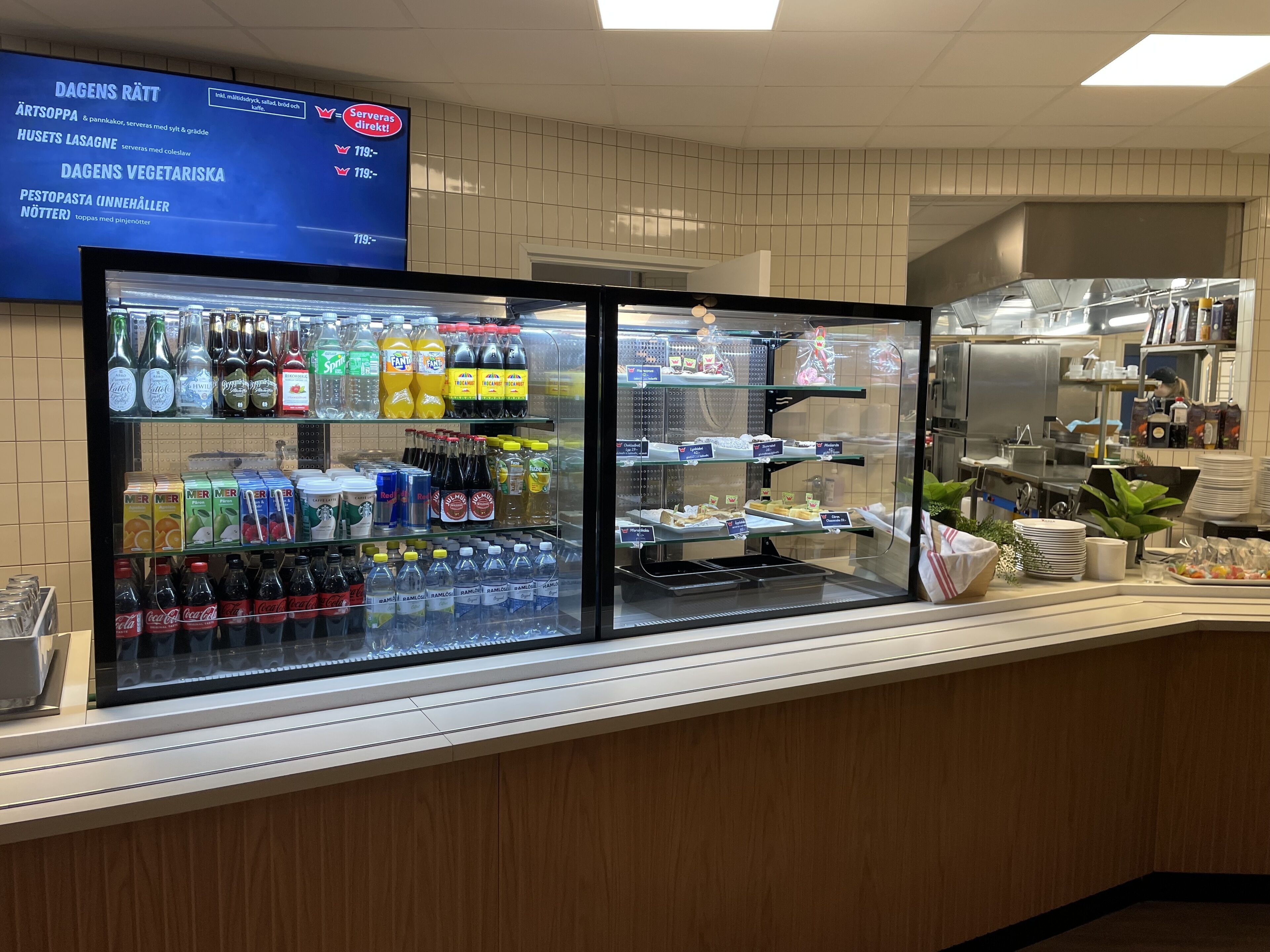 A food display area with refrigerated sections and shelves stocked with beverages and snacks.