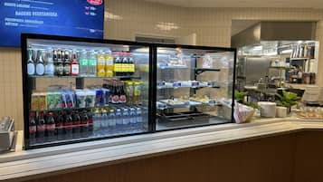 Un área de exhibición de alimentos con secciones refrigeradas y estantes llenos de bebidas y aperitivos.