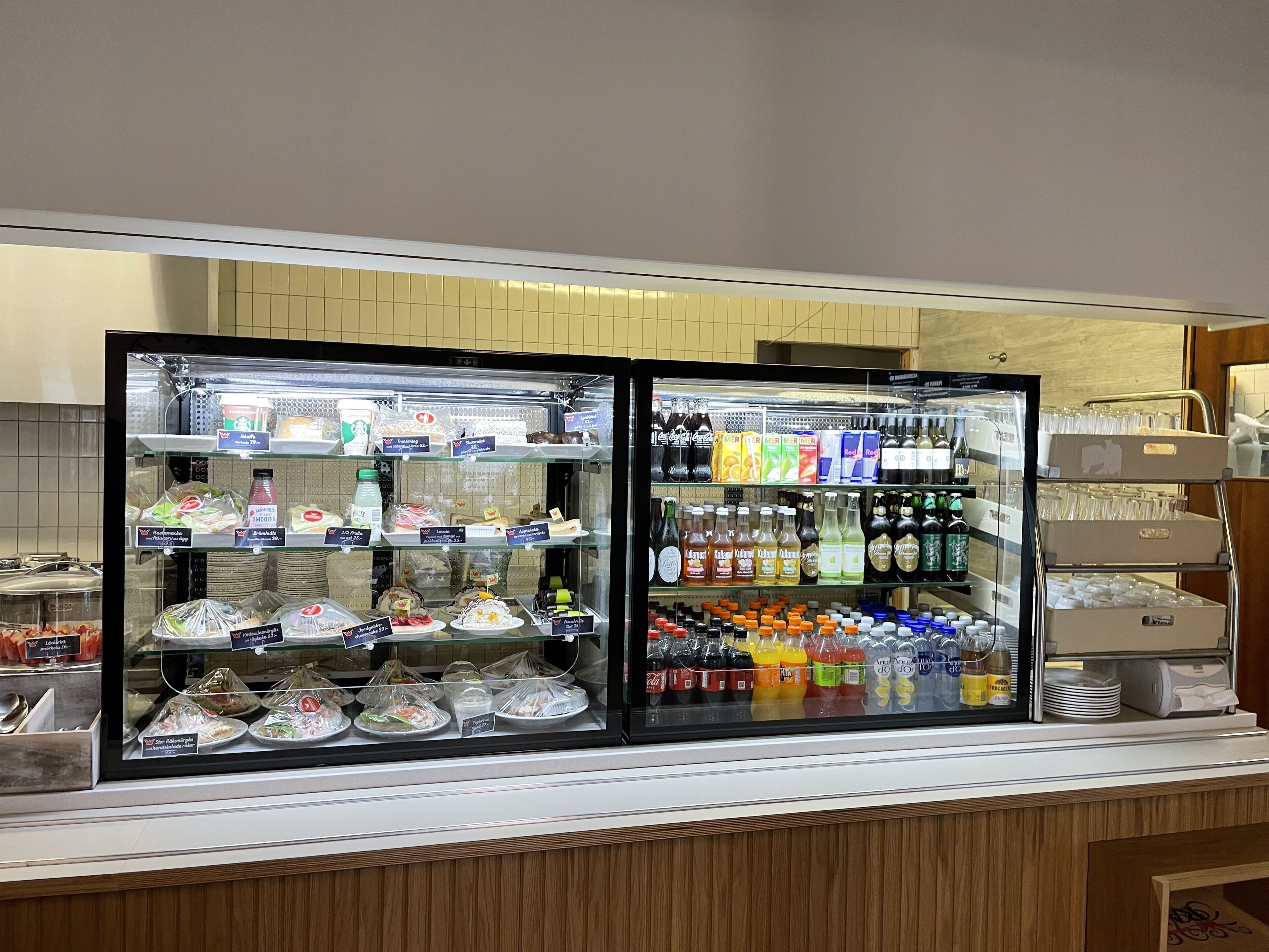 A self-service beverage and food station with refrigerated drinks and a variety of packaged snacks.