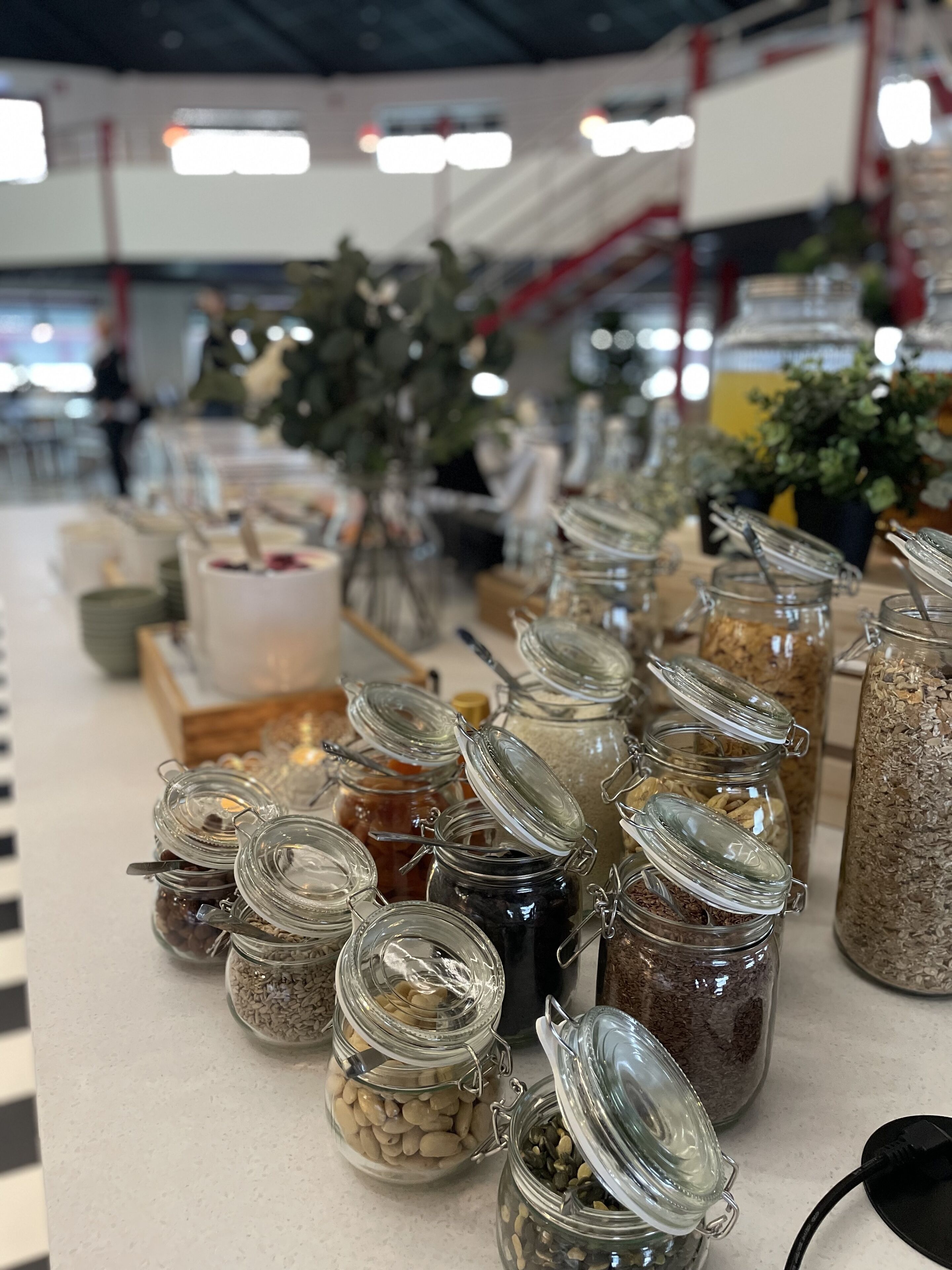 Une table de buffet avec divers aliments présentés dans des bocaux en verre.