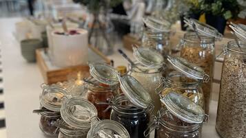 Une table de buffet avec divers aliments présentés dans des bocaux en verre.
