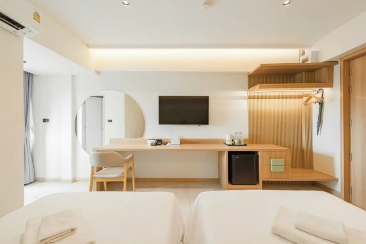 A hotel room with a bed, a desk, a chair, a TV, and a wardrobe.