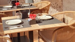 Een buitenplaats om te eten, met rieten stoelen en een tafel voor twee personen, voorzien van een betegelde achterwand en een bakstenen muur.