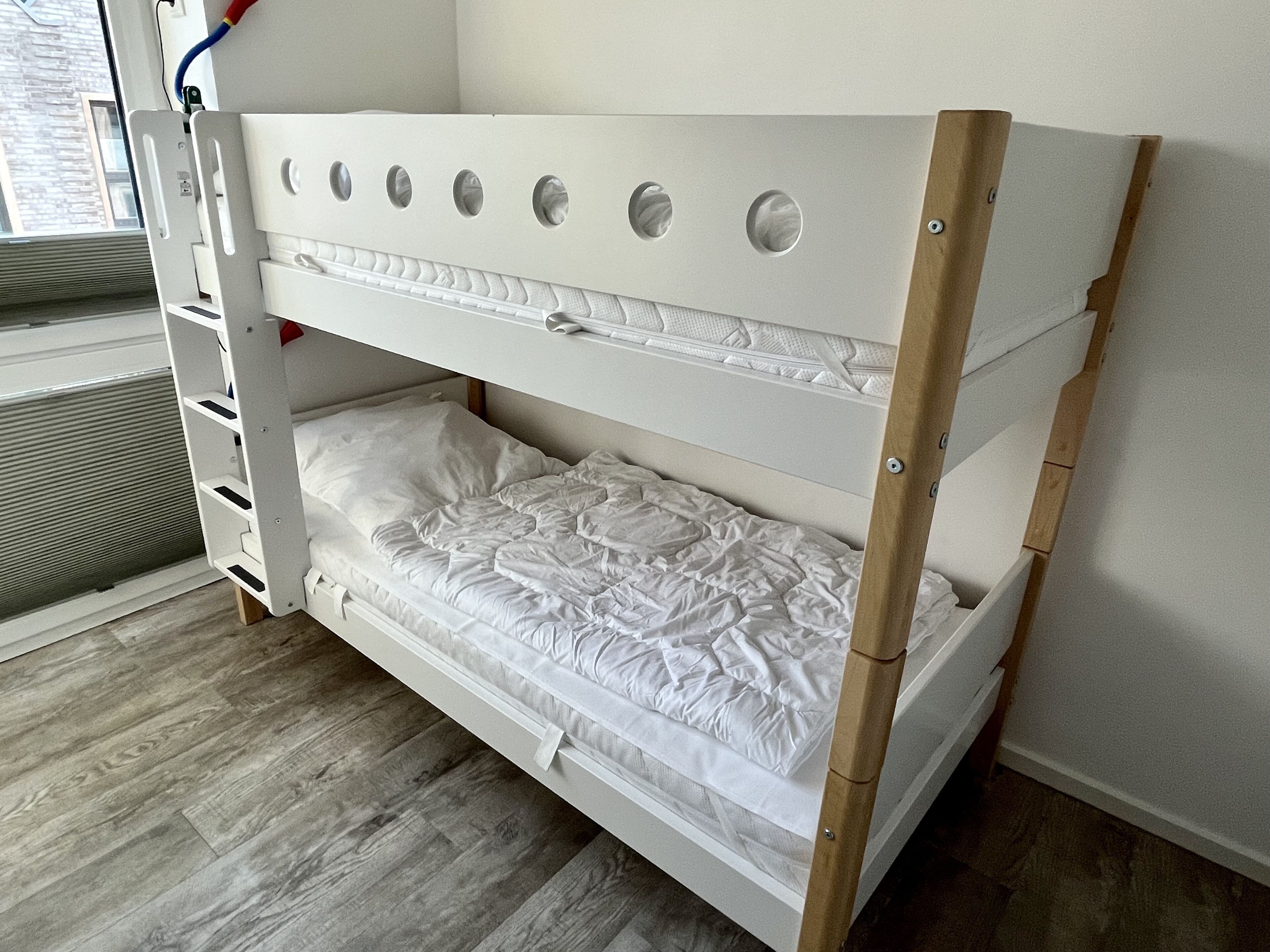 Ein Stockbett mit Holzrahmen und einer Matratze mit gesteppter Auflage.