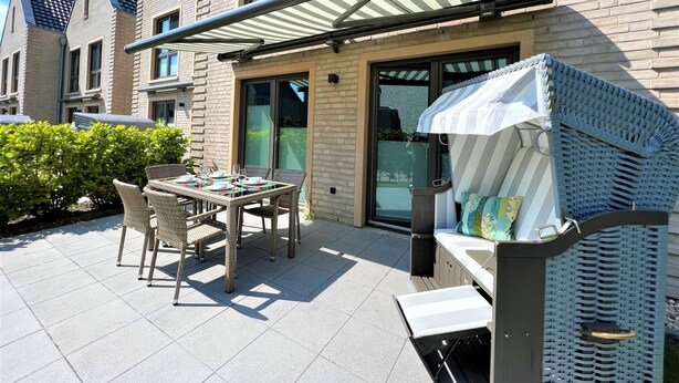 A patio with a table and chairs, a grill, and a covered seating area.