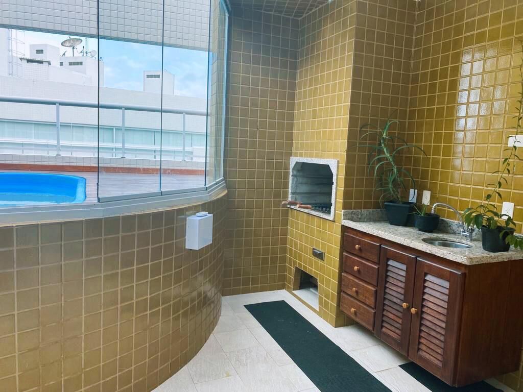 Un baño con baldosas amarillas, una ventana, un lavamanos, un espejo y una planta pequeña.