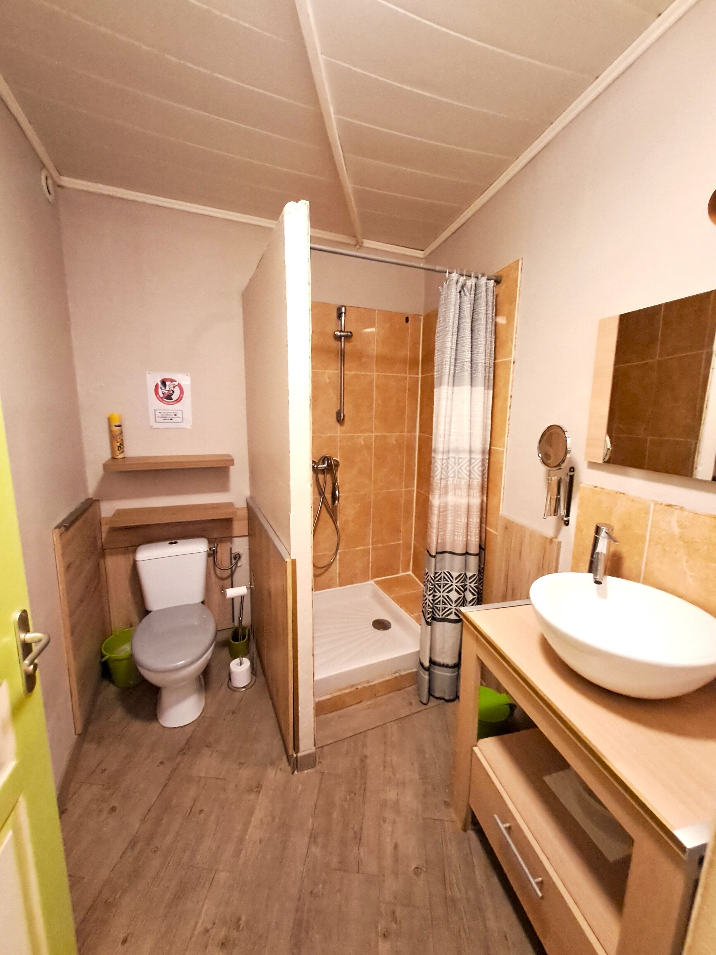 A compact bathroom with a toilet, shower, and sink.
