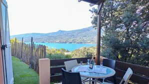 Um terraço com mesa e cadeiras, oferecendo uma vista panorâmica de um lago e montanhas.