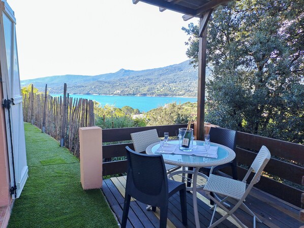 A terrace with a table and chairs, overlooking a scenic view of a lake and mountains.