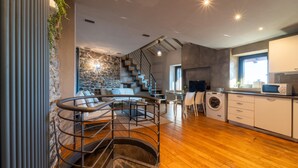 Une cuisine moderne avec un mur d’accent en pierre, un plancher en bois et un lave-linge encastré.
