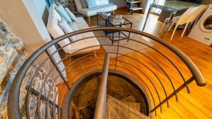Un escalier en colimaçon avec une rampe en métal, des marches en bois et un mur en pierre.