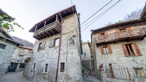 Une ruelle étroite pavée, bordée de bâtiments en pierre dotés de volets en bois et de balcons.