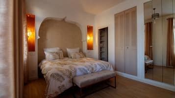 Un dormitorio con una cama grande, un banco, un armario y un espejo.