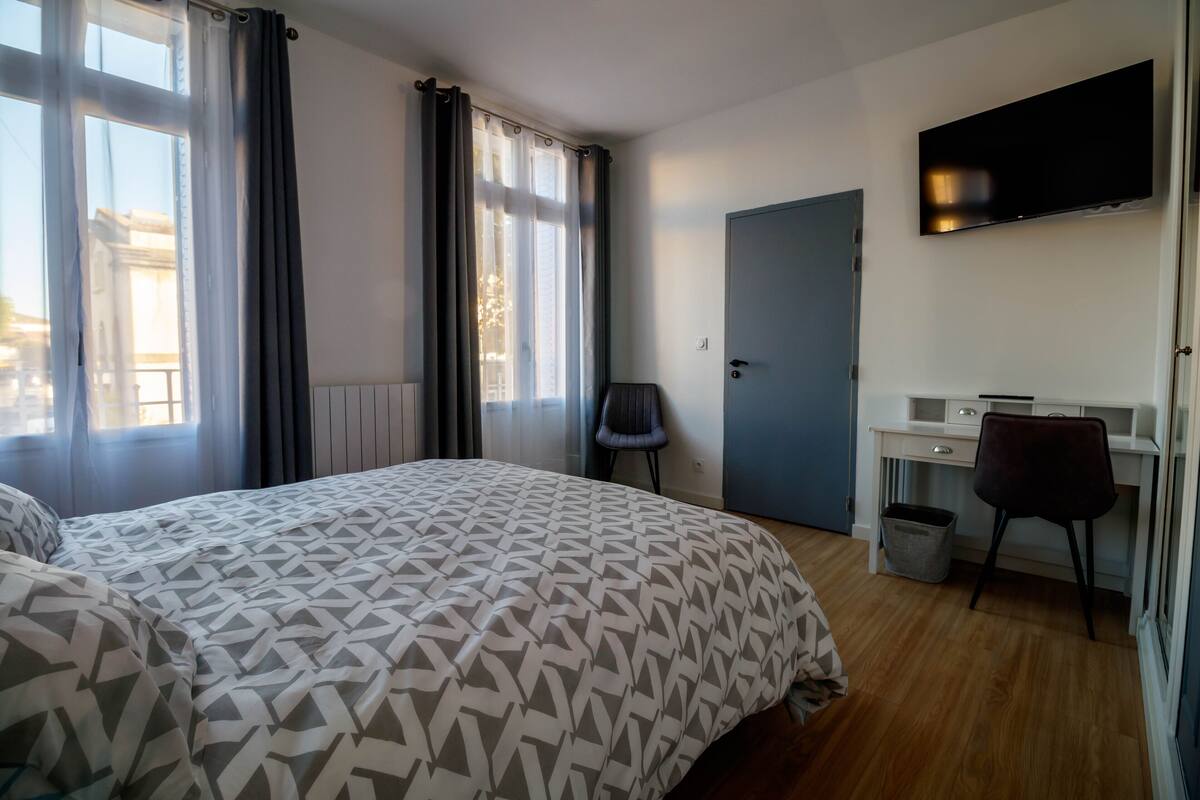 Una habitación de hotel con cama, escritorio, silla, televisor y puerta.
