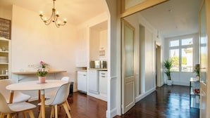 A spacious kitchen with white cabinetry, a dining area with a table and chairs, and a chandelier.