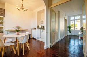 A spacious kitchen with white cabinetry, a dining area with a table and chairs, and a chandelier.
