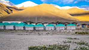 A row of yurts with green roofs, set against a backdrop of mountains and a clear sky. - Martsemik Camping Spangmik (Leh)