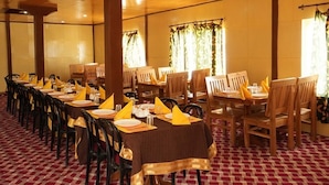 A banquet hall with long tables set for dining, wooden chairs, and a patterned carpet. - Martsemik Camping Spangmik (Leh)