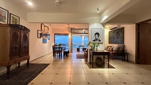 A spacious living room with a dining area, a view of the cityscape, and a ceiling fan. - Stunning Art filled / Water View apt in Kochi (Ernakulam)