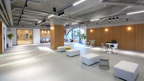 A spacious, modern office with a clean, minimalist design, featuring white furniture, wooden accents, and ample natural light. - MGM Hotel (Gangneung)