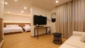 A hotel room with two beds, a TV, a small table, a sofa, and a curtain. - MGM Hotel (Gangneung)