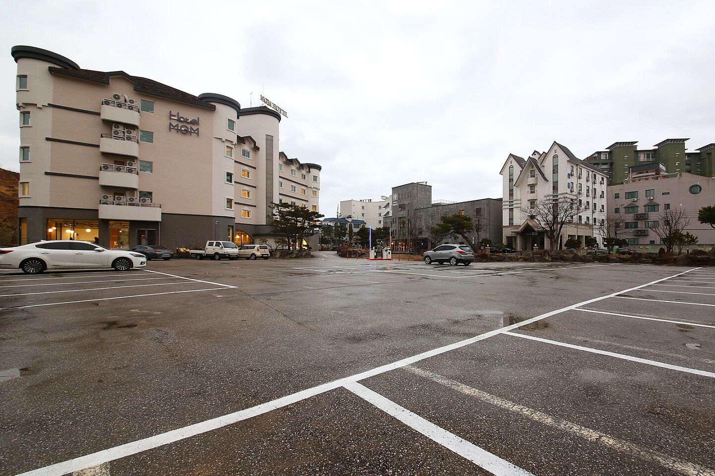 A hotel with multiple floors and a parking lot in front.