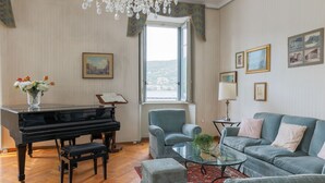 A living room with a grand piano, a sofa, a glass coffee table, and a chandelier.