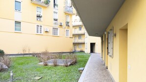 Un pasillo con un edificio amarillo a un lado y un área verde al otro.