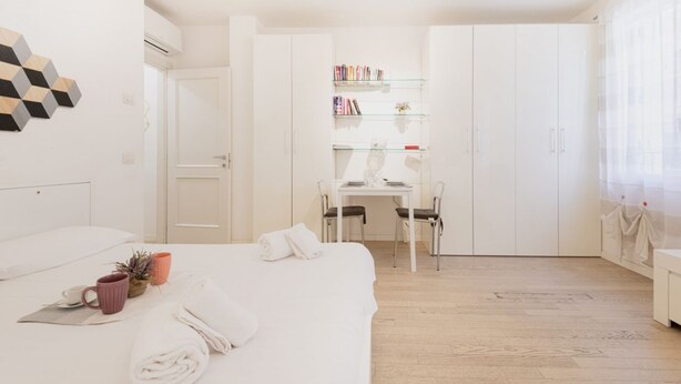 Un dormitorio moderno con cama, escritorio y estantería.