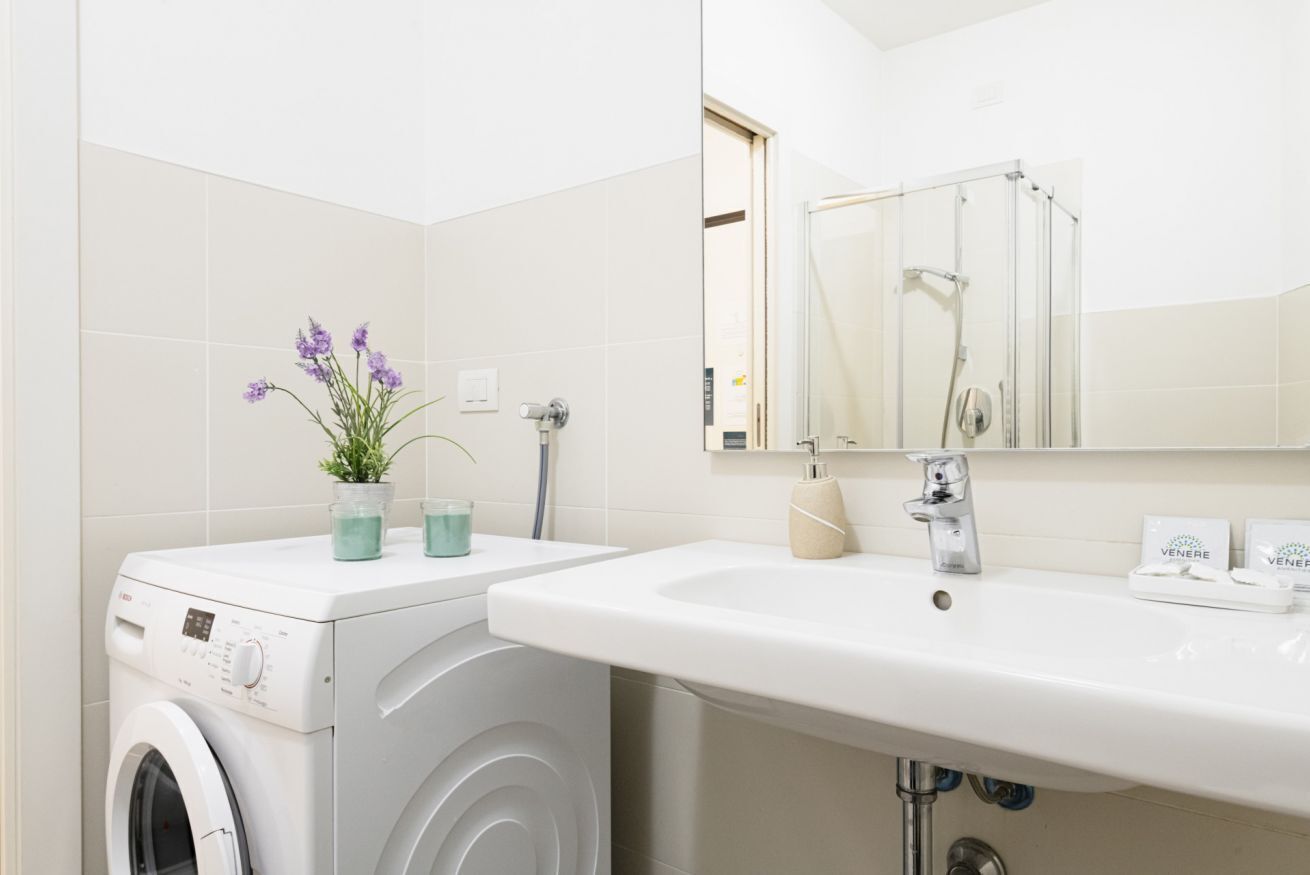 Un baño moderno con lavadora, lavamanos y ducha.
