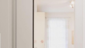 Una habitación con cama, mesita de noche y ventana con cortinas.