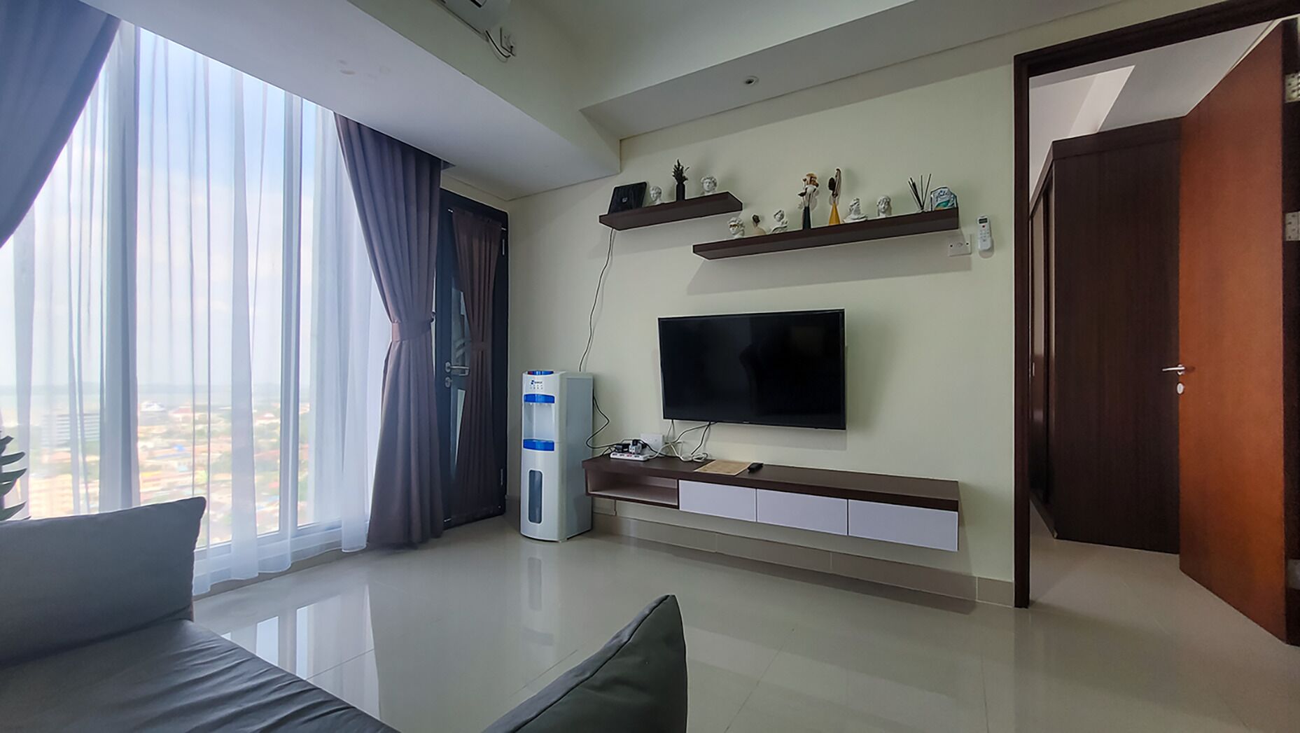 A modern living room with a large TV, a built-in sound system, and a view of the city through large windows.
