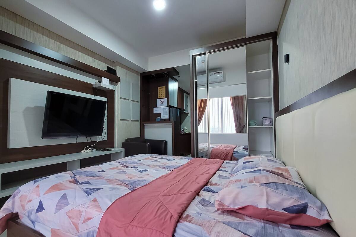 Ein Hotelzimmer mit Bett, Fernseher, Schreibtisch und Kleiderschrank.