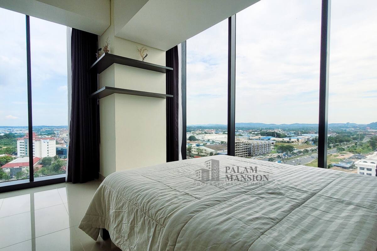 Ein Schlafzimmer mit einem großen Bett, Blick auf eine Stadtansicht und ein Balkon mit Vorhang.