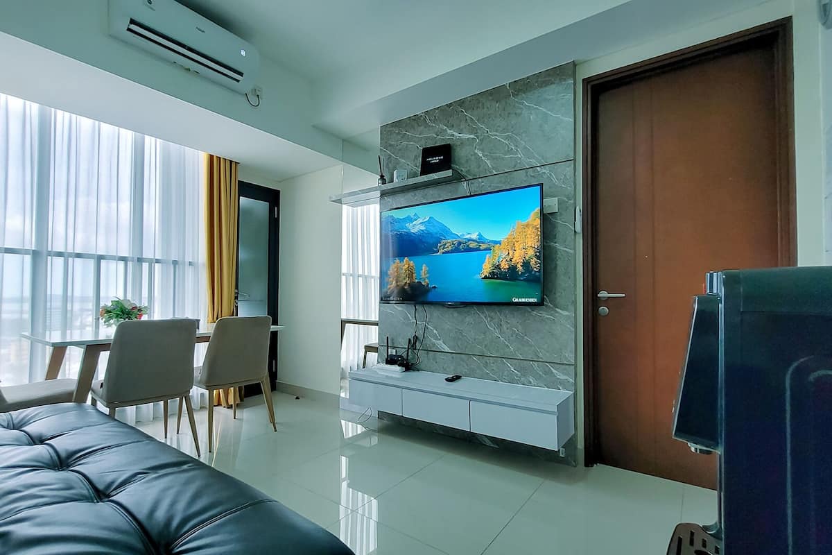 Ein modernes Wohnzimmer mit Flachbildfernseher an einer Marmorwand, einer Couch, einem Essbereich mit Stühlen und einer Tür.