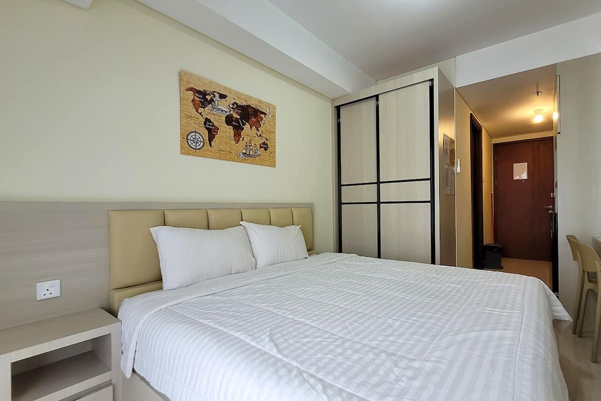 Ein Hotelzimmer mit einem Bett, einem Schreibtisch, einem Stuhl, einem Wandbild mit einer Weltkarte und einer Schiebetür.