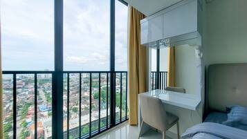Habitación de hotel moderna con un balcón grande, un escritorio y una cama.