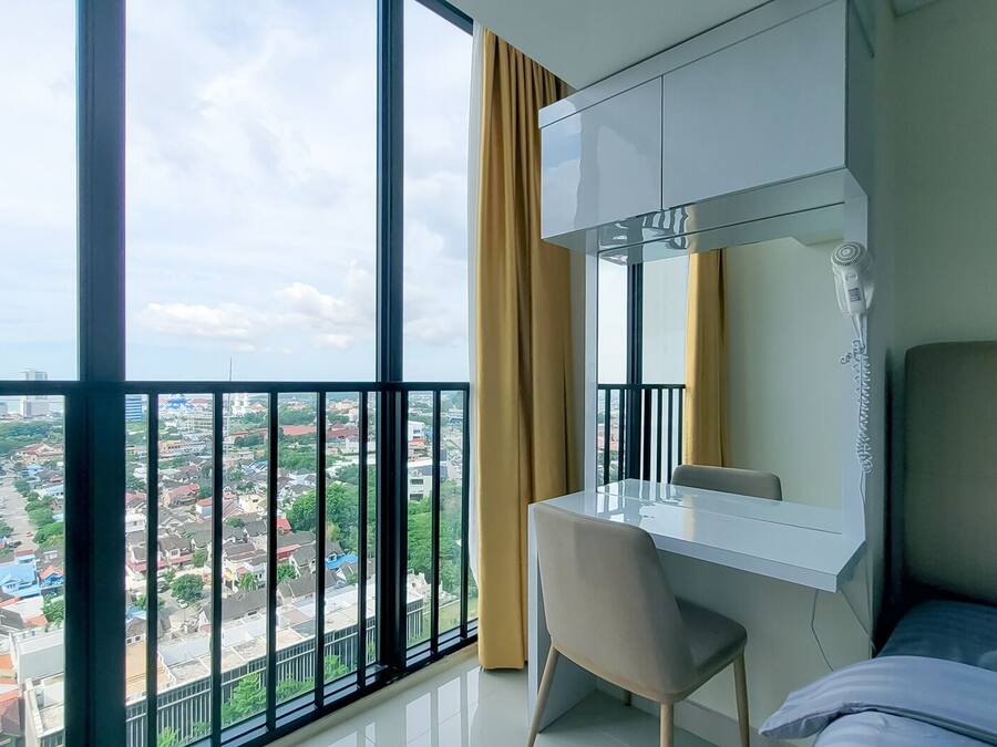 Habitación de hotel moderna con un balcón grande, un escritorio y una cama.