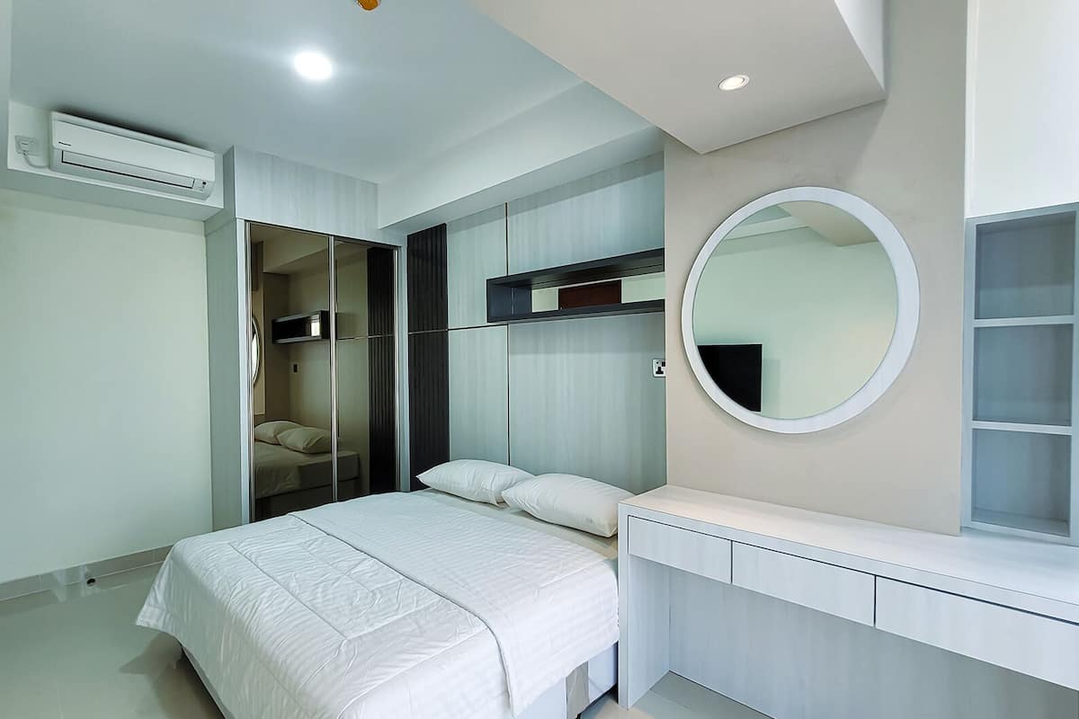 Ein modernes Schlafzimmer mit einem Bett, einem Fernseher, einem Kleiderschrank und einem Spiegel.