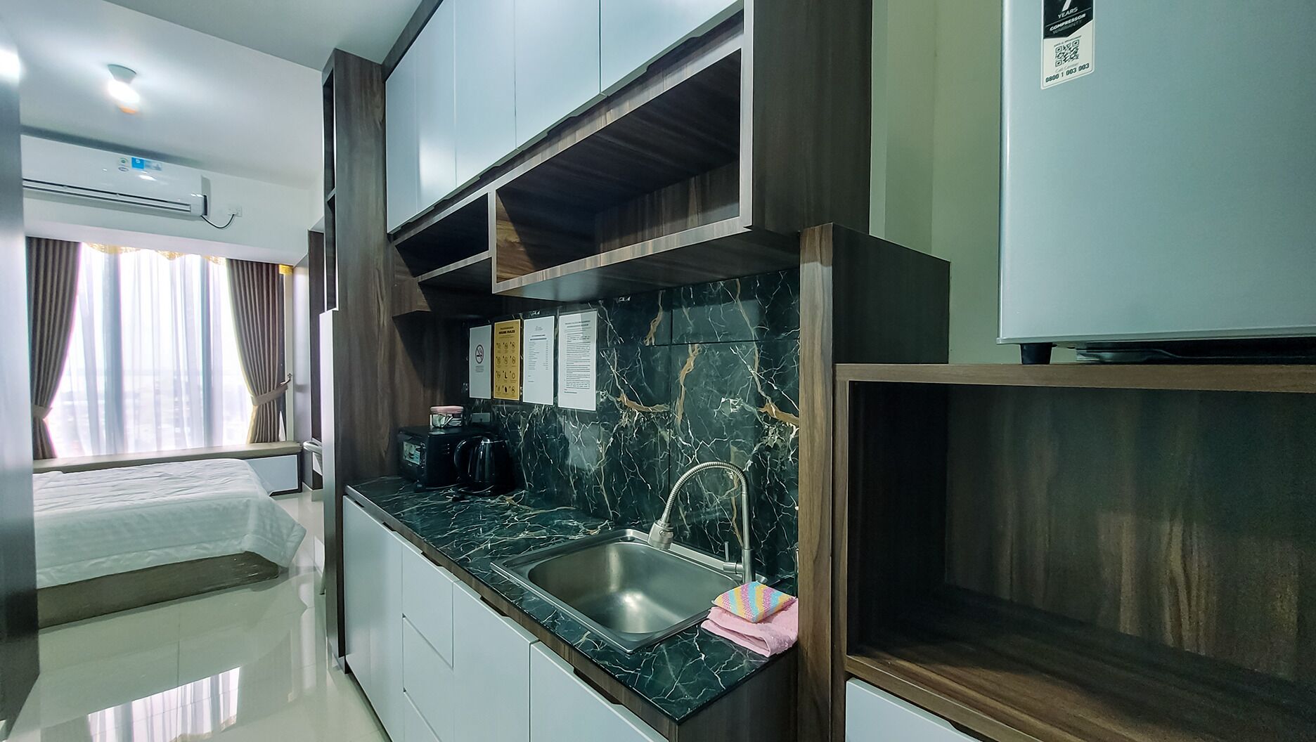 A modern kitchen with a marble countertop, stainless steel sink, and a built-in oven.
