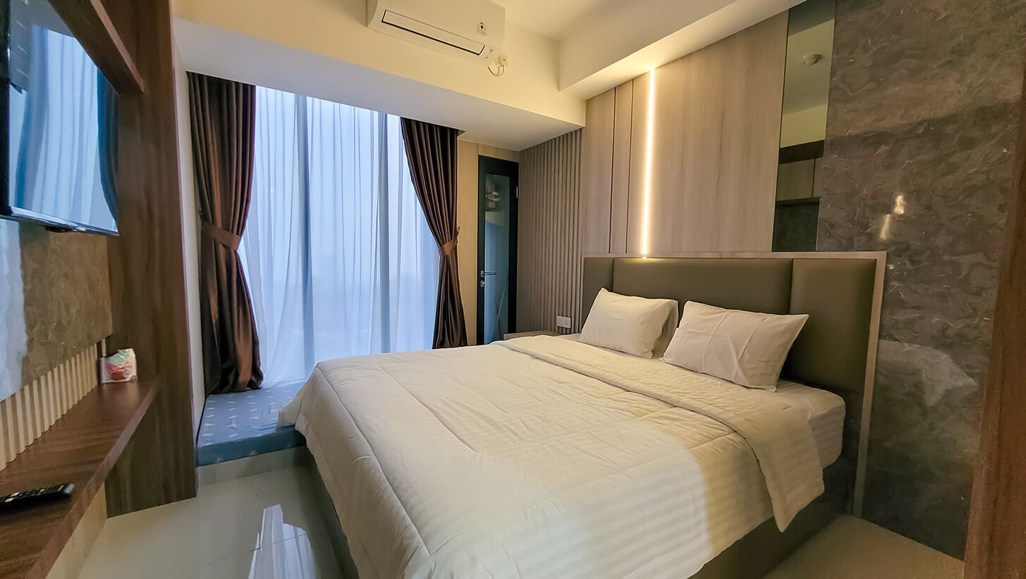 Una habitación de hotel moderna con una cama grande, televisor y baño con espejo y toallero.