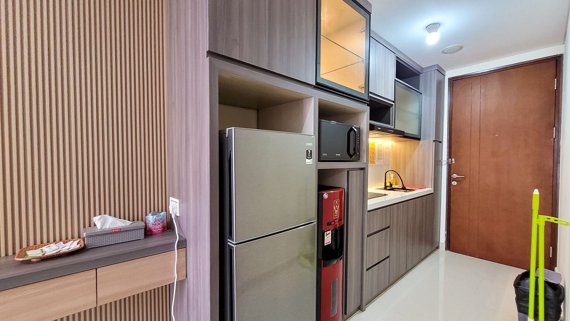 A compact kitchen with built-in appliances, a microwave, and a sink.