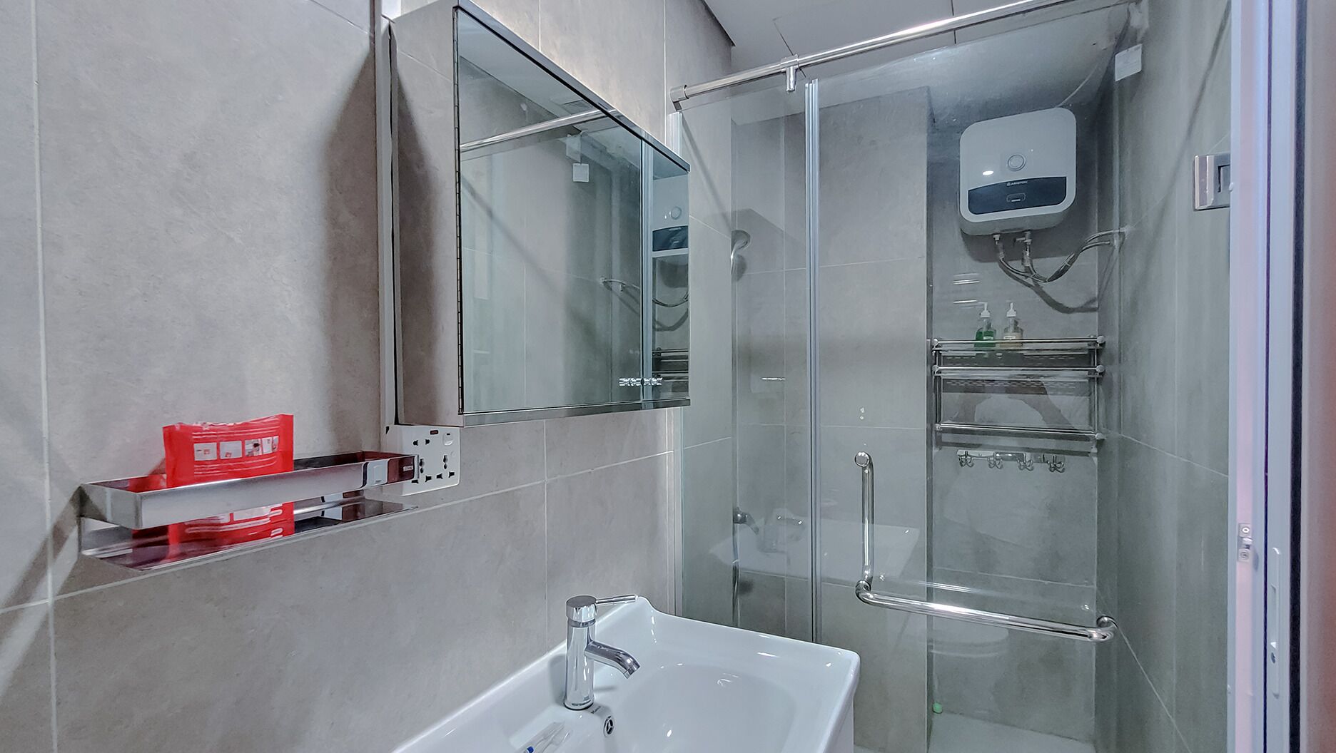 A modern bathroom with a glass shower enclosure, a white sink, and a mirror above the sink.