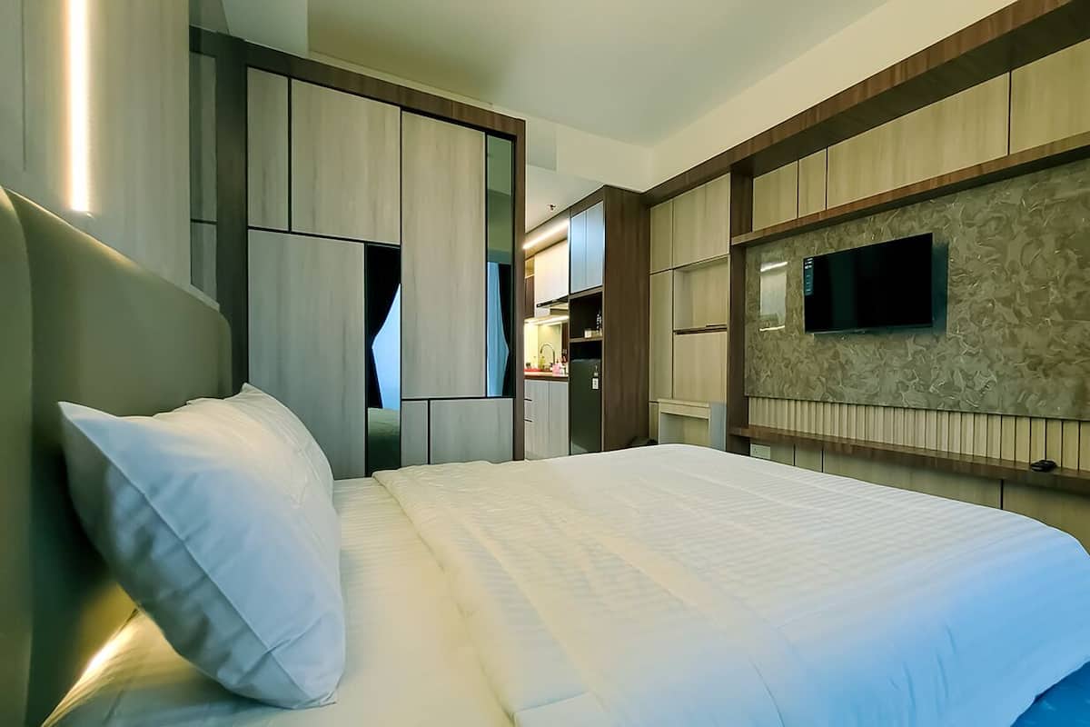 Ein Hotelzimmer mit Bett, Wandfernseher und integriertem Wandschrank.