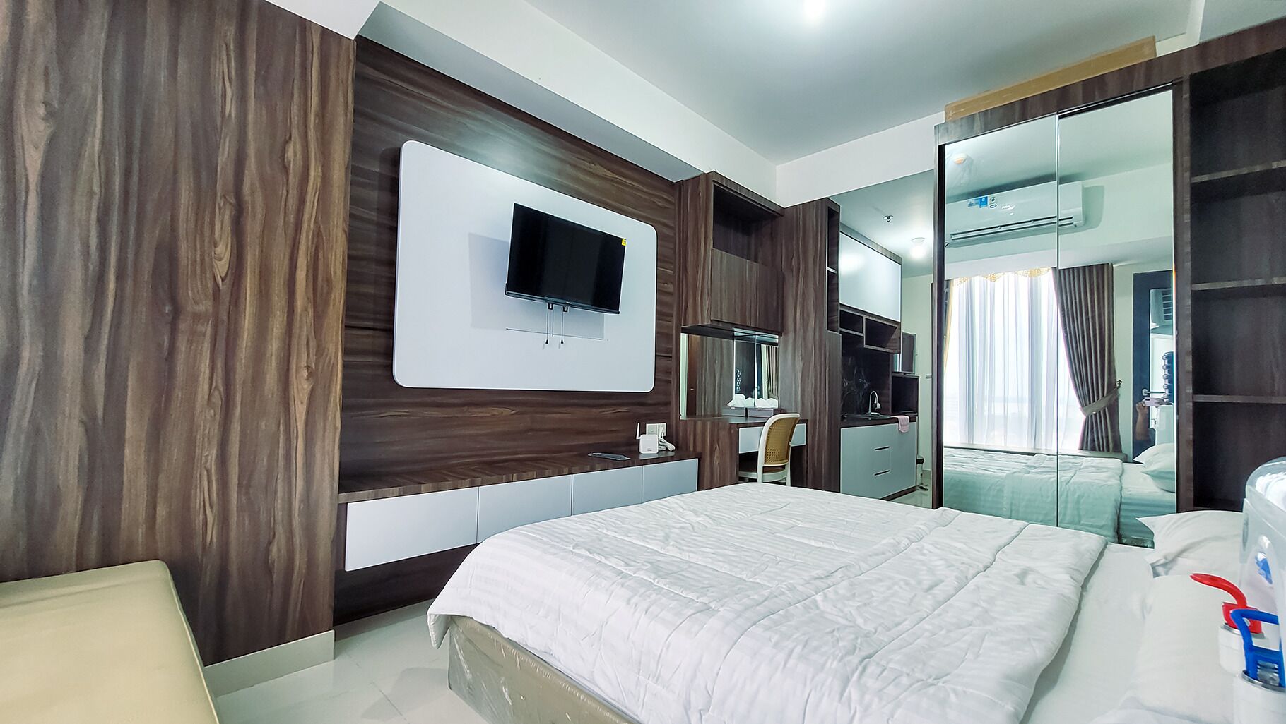 Quarto de hotel moderno com uma cama grande, televisão de tela plana na parede, toucador com espelho e closet espaçoso.